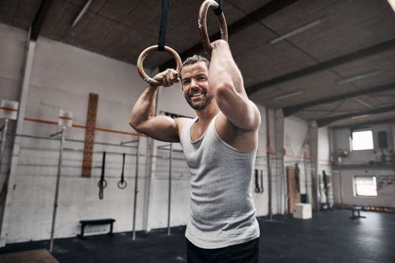 smiling-man-resting-after-exercising-on-rings