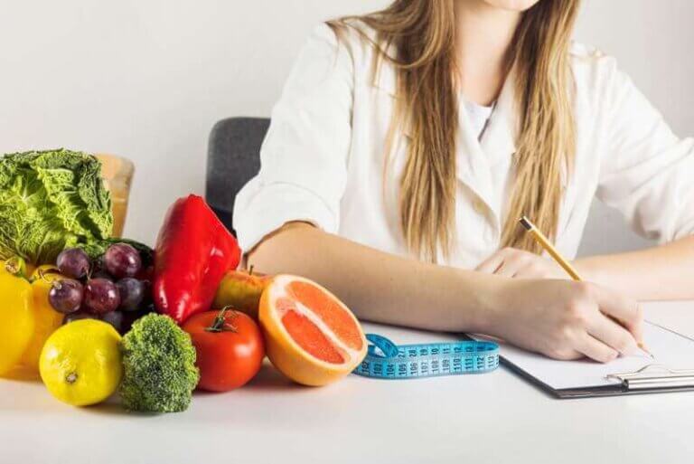 dietician-s-hand-writing-clipboard-with-healthy-food-desk