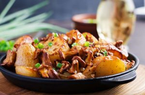 Baked potatoes with garlic, herbs and fried chanterelles in a cast iron skillet