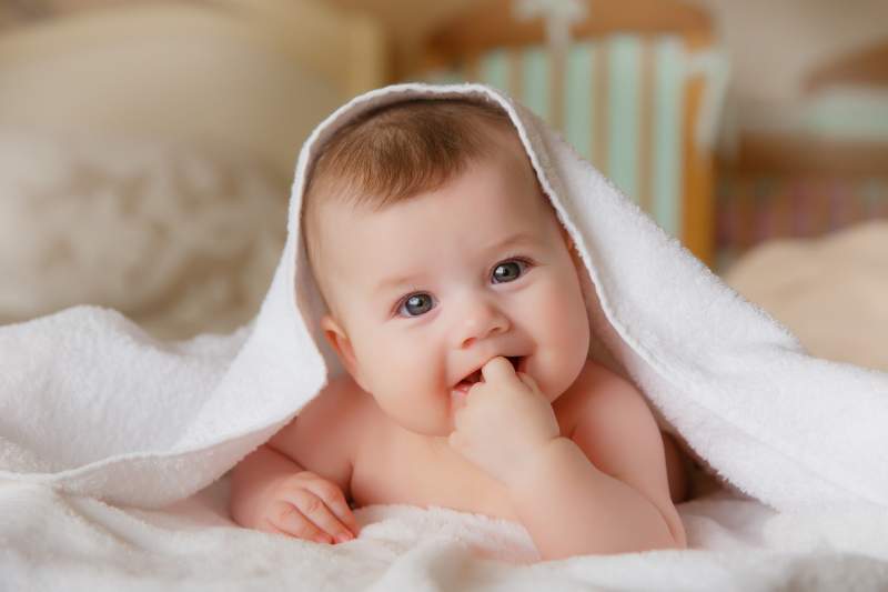 Happy smiling baby in a towel after bathing