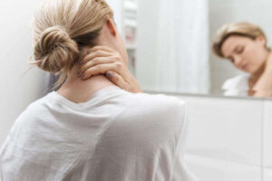 Woman looking in the mirror having neck pain