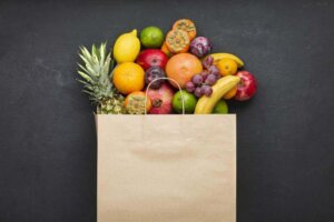 Assortment of fruits in a paper bag on black concrete. concept of vitamins in human diet