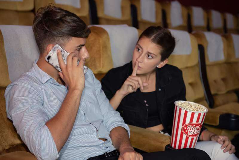 Young man talking on mobile phone during see movie
