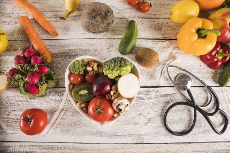 Heart shape container with healthy vegetables near stethoscope