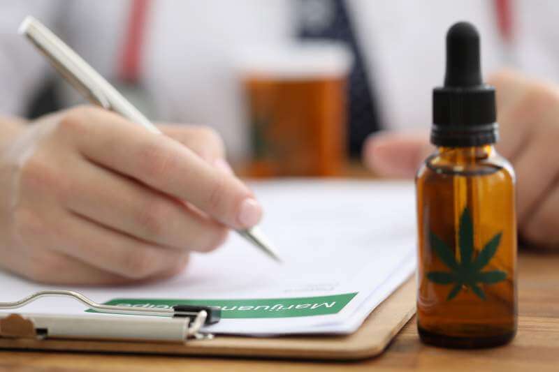 Closeup doctors hand writing prescription for hemp