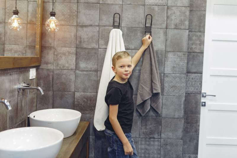 small-boy-hanging-up-towel-in-bathroom