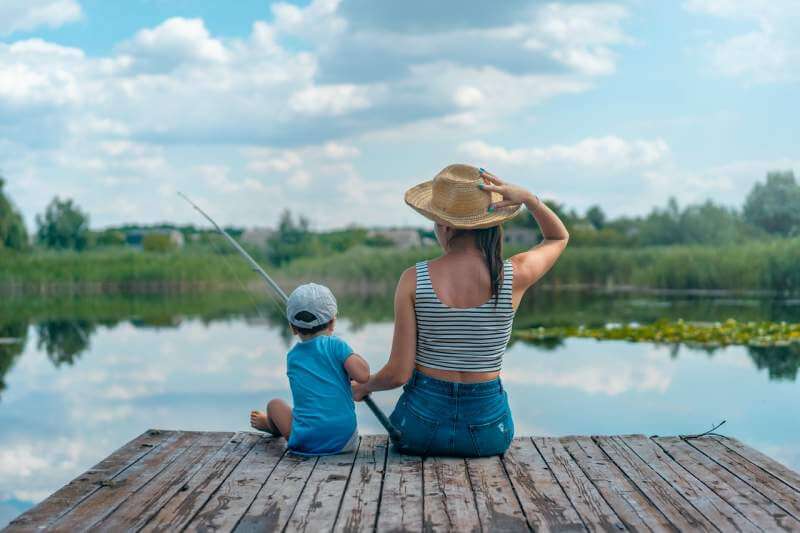 woman-and-boy-sitting-on-dock-holding-fishing-rod