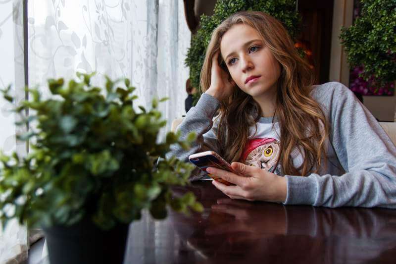 girl-teen-café-smartphone-sorrow